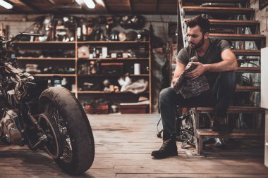 Atölye merdivenlerde oturan motorcu
