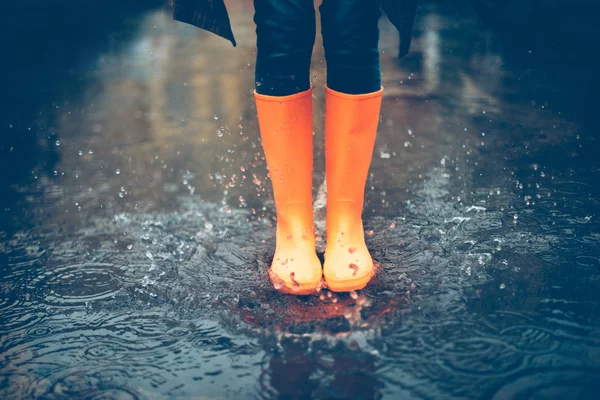 Woman legs in orange rubber boots — Stock fotografie