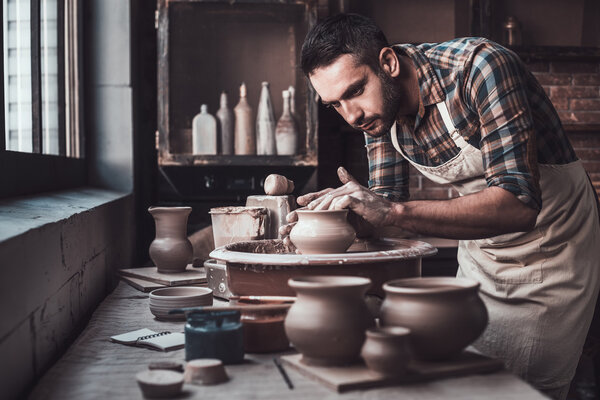 man in apron making ceramic jug 