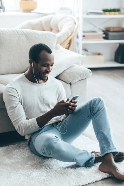 Afrykański mężczyzna patrząc na telefon komórkowy — Zdjęcie stockowe