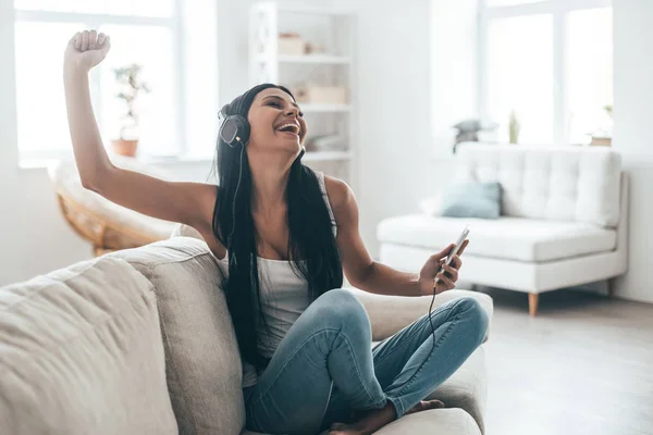 Vrouw in hoofdtelefoons houden slimme telefoon — Stockfoto