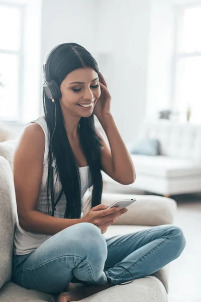 woman in headphones holding smart phone