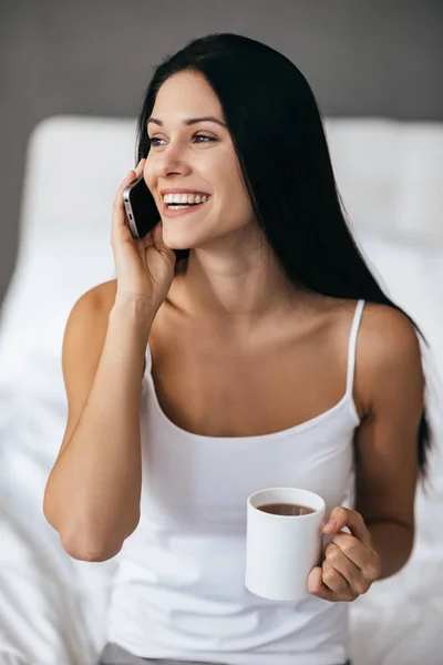 Mujer sosteniendo taza y hablando por teléfono — Foto de Stock