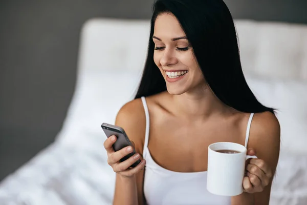 Frau mit Tasse und Smartphone — Stockfoto