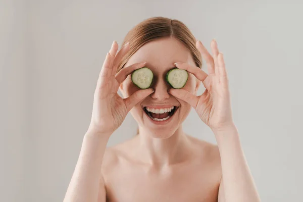 Beautiful woman holding cucumber slices — Stock Photo, Image