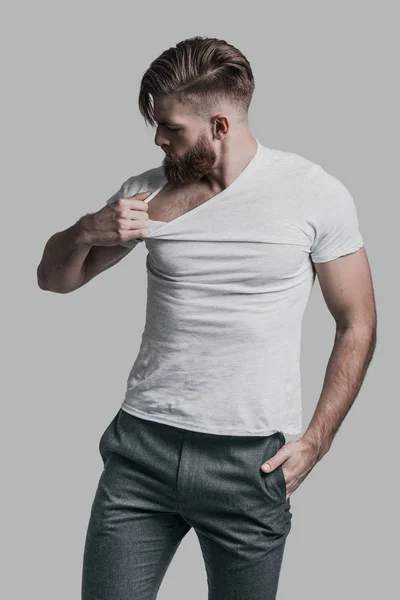 Homme à la barbe tirant son T-shirt — Photo