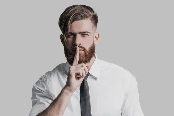 Young businessman holding finger on lips — Stock Photo, Image
