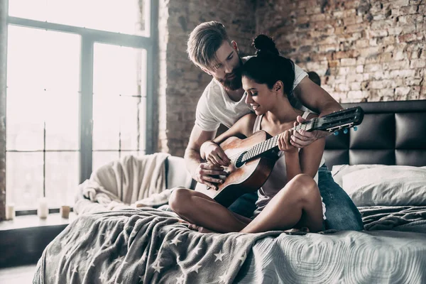 Mężczyzna nauczanie kobieta się grać na gitarze — Zdjęcie stockowe