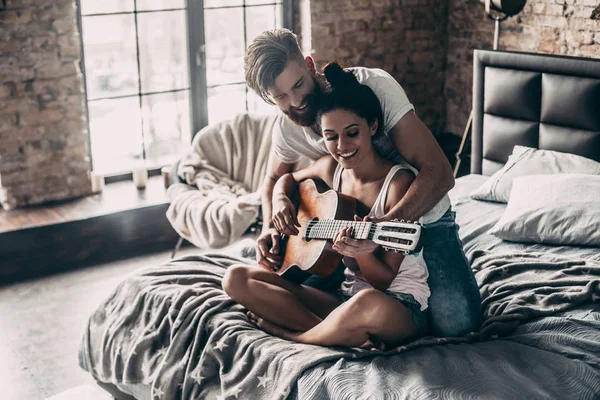 Hombre enseñando a la mujer a tocar la guitarra — Foto de Stock