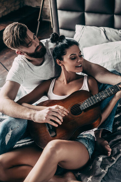 man teaching woman to play guitar