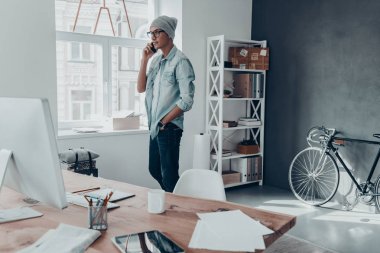 adam akıllı telefonda konuşurken şapkalı