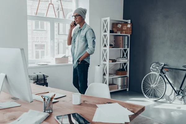 adam akıllı telefonda konuşurken şapkalı