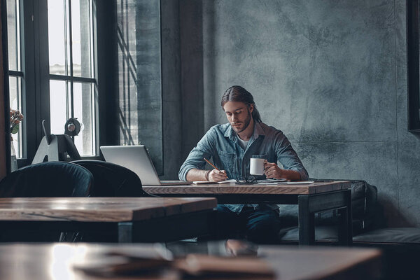 человек пишет заметки и пьет чай
