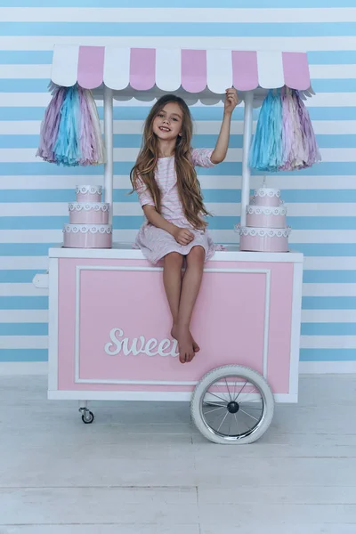 Little girl sitting on candy cart — Stock Photo, Image