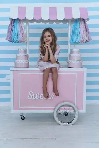 Little girl sitting on candy cart — Stock Photo, Image