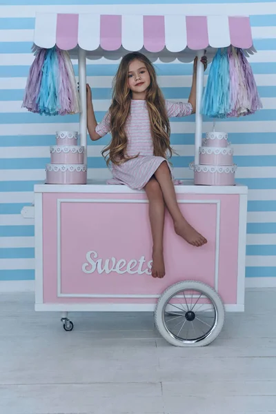 Little girl sitting on candy cart — Stock Photo, Image