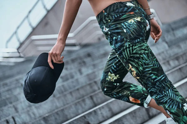 Sportive woman in leggings carrying a cap — Stock Photo, Image