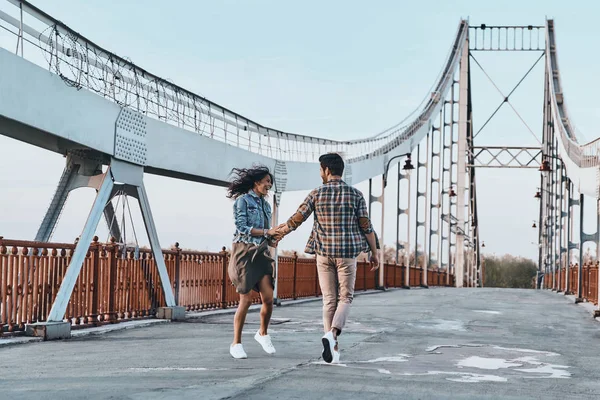 Пара тримає руки і ходить на мосту — стокове фото
