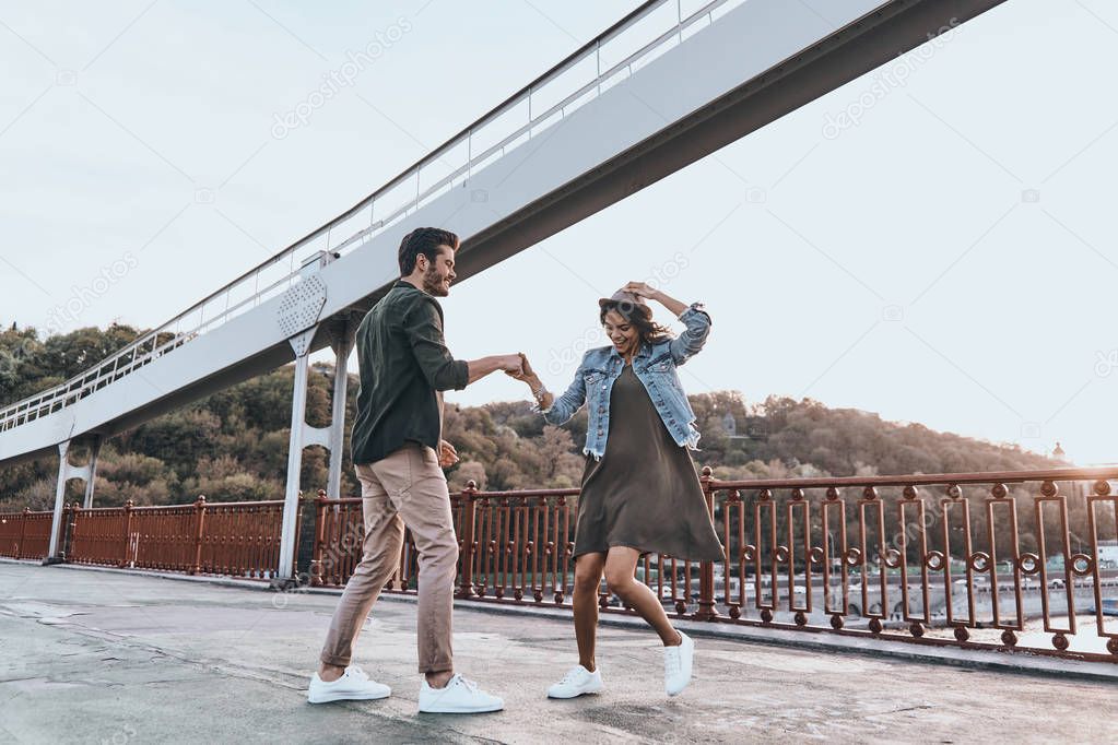 casual couple dancing on bridge