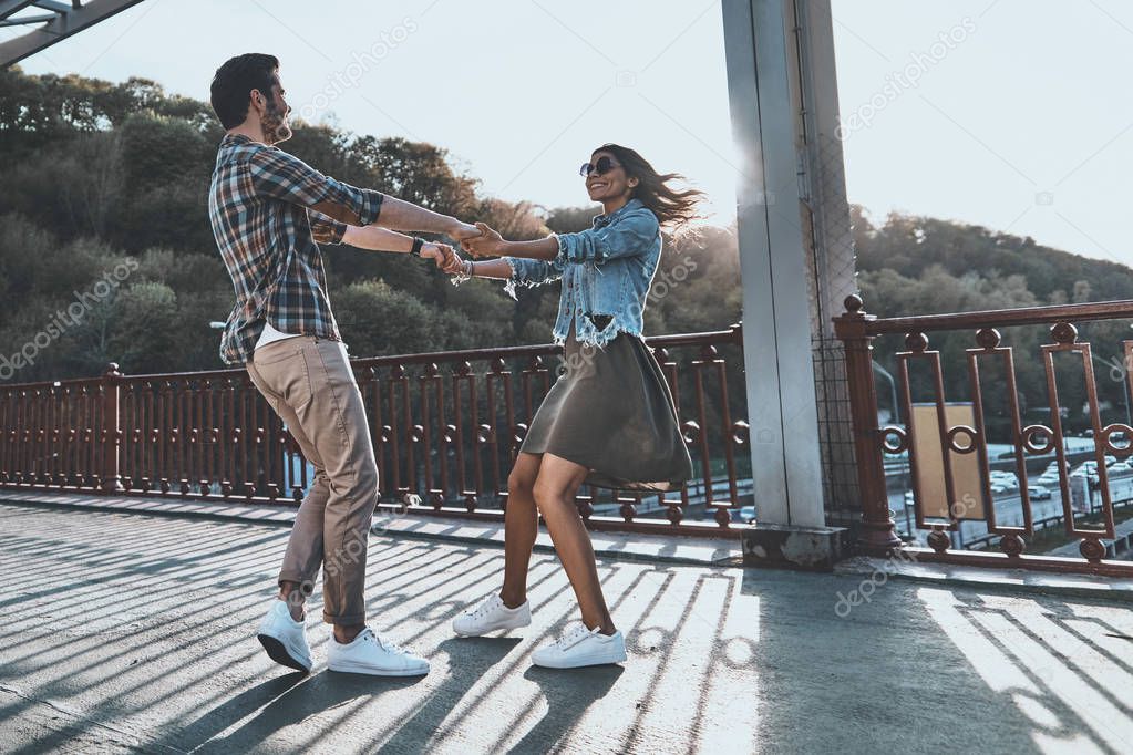 stylish young couple dancing on the bridge