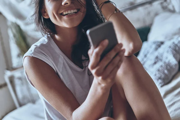 Женщина смеется и держит смартфон — стоковое фото