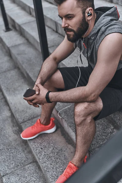 Hombre en ropa deportiva escuchando música — Foto de Stock