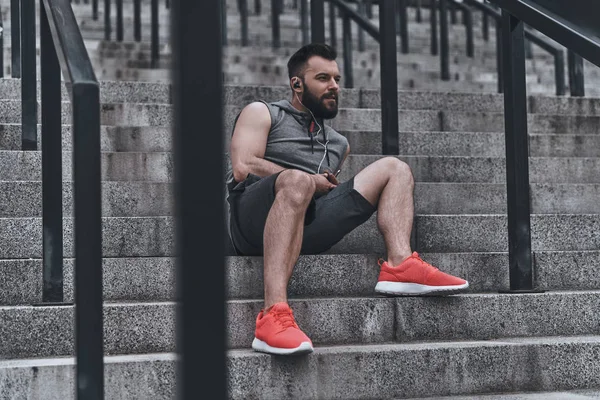 Hombre en ropa deportiva escuchando música — Foto de Stock