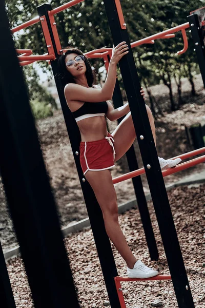 Sporty woman standing on horizontal bars — Stock Photo, Image