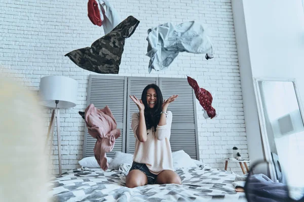 Frau sitzt auf Bett und wirft Kleidung — Stockfoto