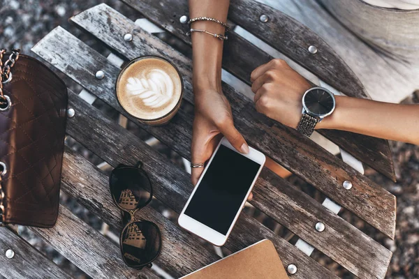 Женщина сидит в кафе и просматривает мобильный — стоковое фото