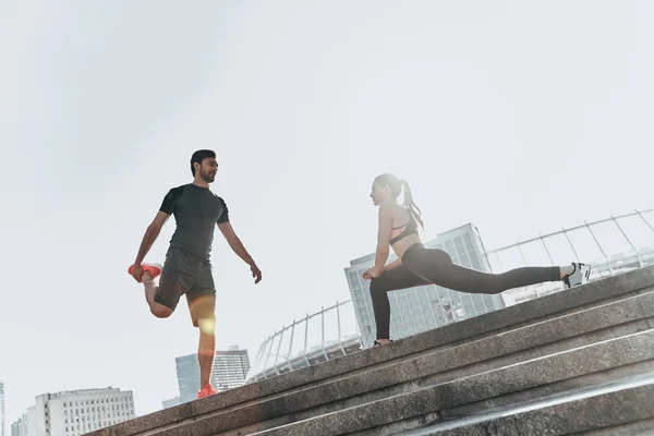 Casal esportivo fazendo exercícios de alongamento — Fotografia de Stock