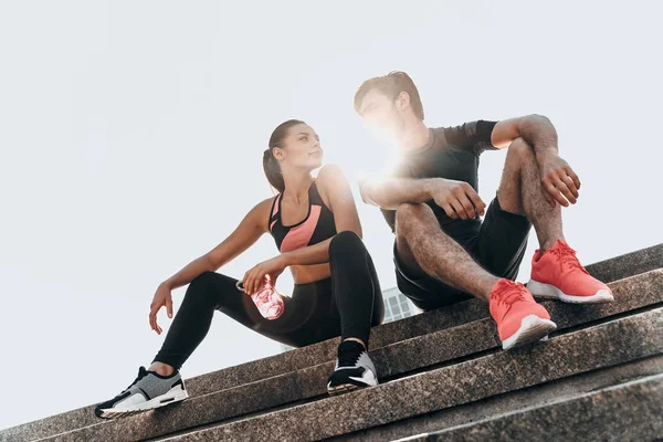 Sportive couple sitting on stairs — Stock Photo, Image