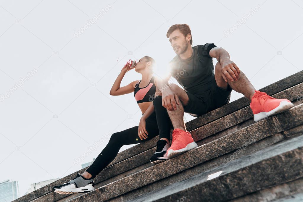 sportive couple sitting on stairs