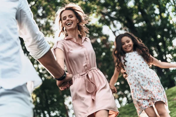 Menina correndo com os pais no parque — Fotografia de Stock