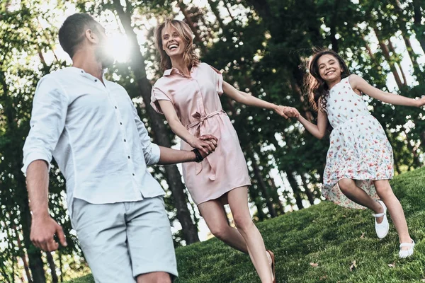 Fille courir avec les parents dans le parc — Photo