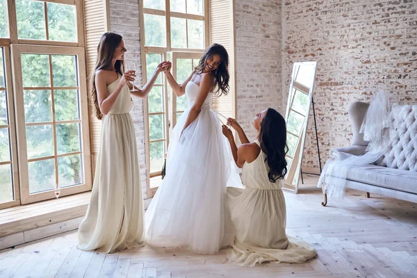 bridesmaids helping bride to get dressed