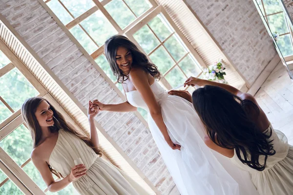 bridesmaids helping bride to get dressed