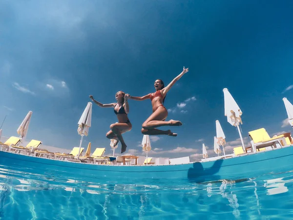 Mujeres en bikini saltando en la piscina — Foto de Stock
