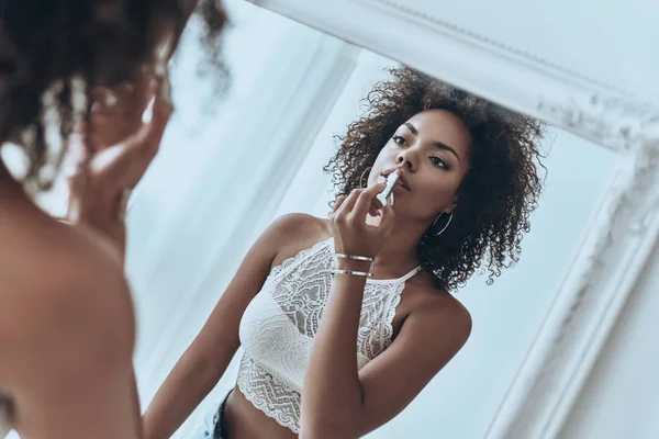 Woman looking at mirror and putting on lipstick — Stock Photo, Image