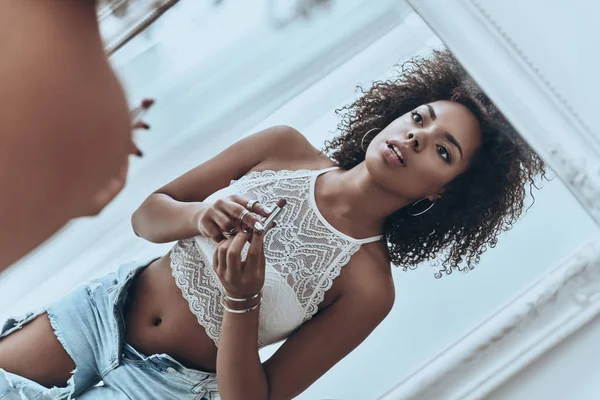 Woman looking at mirror and putting on lipstick — Stock Photo, Image