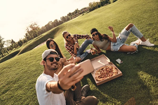 Друзья едят пиццу на пикнике — стоковое фото