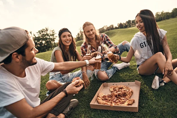 Vrienden eten pizza op picknick — Stockfoto