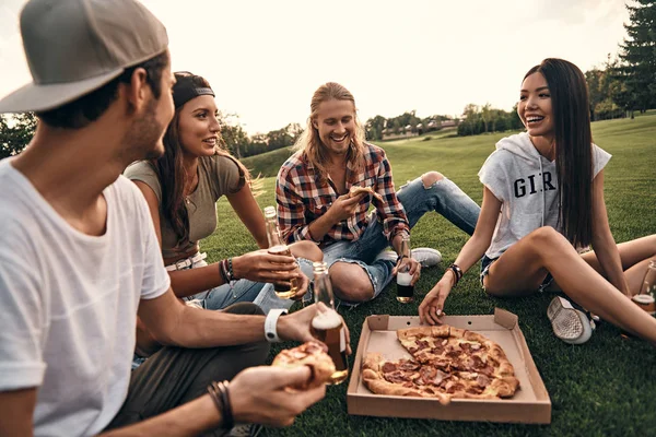 Vänner som äter pizza på picknick — Stockfoto