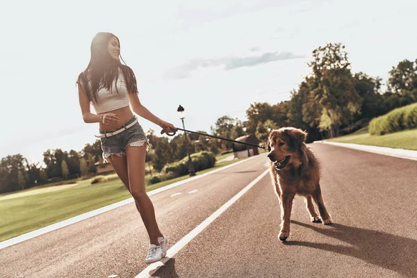 Mulher em calções de ganga correndo com cão — Fotografia de Stock