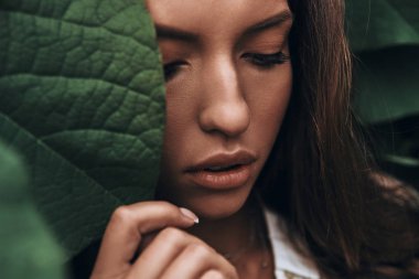 woman face among green leaves