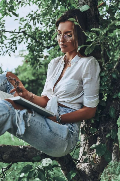 Женщина сидит на ветке дерева — стоковое фото