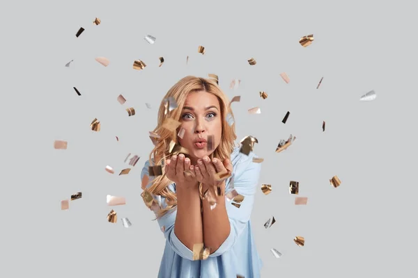 Woman blowing confetti in studio — Stock Photo, Image