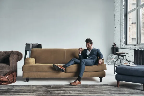 Όμορφος άντρας με κοστούμι που κάθεται στον καναπέ — Φωτογραφία Αρχείου