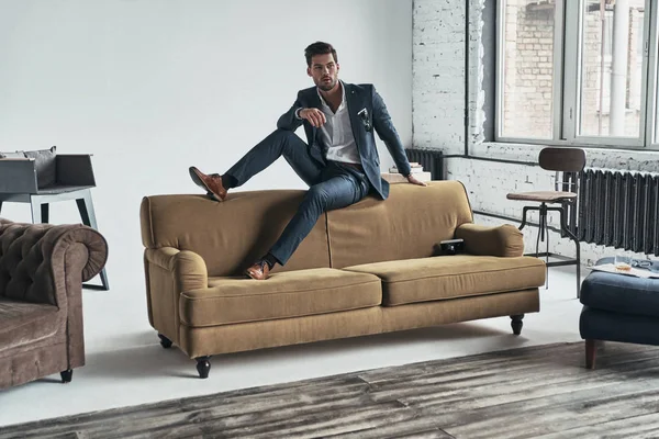 Przystojny mężczyzna w garniturze, siedząc na kanapie — Zdjęcie stockowe