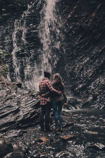 Pár v lásce všeobjímající poblíž vodopád — Stock fotografie
